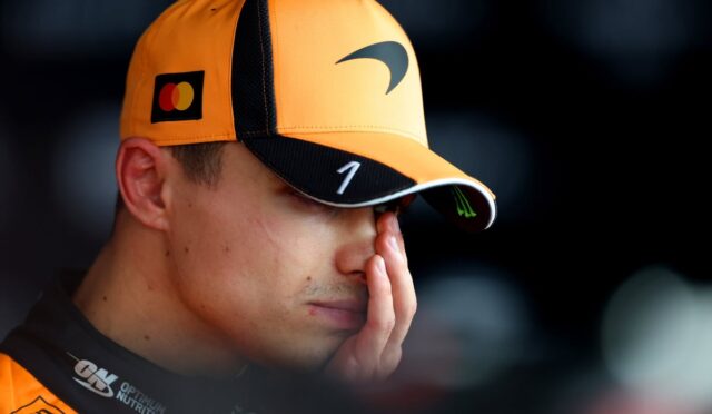 Close-up of a person wearing an orange cap with a MasterCard logo, resting their face in their hand in a tired or contemplative moment.