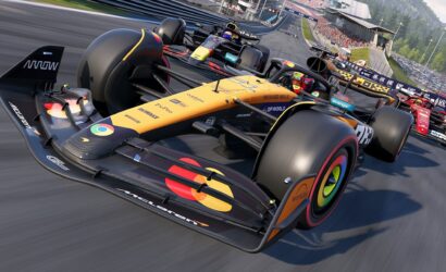 Close-up of a yellow McLaren Formula 1 car leading a race, other cars close behind on a busy track with grandstands in the background signaling high-speed competition