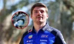 Portrait of a male race driver in a blue sponsor racing suit outdoors, with an inset circle showing a close-up of his helmet.