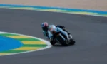 Motorcycle racer leaning into a turn on a race track.