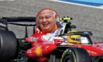 Red Ferrari Formula 1 car on a race track with a circular inset of a smiling man's face in the cockpit area.