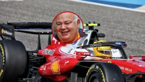 Red Ferrari Formula 1 car on a race track with a circular inset of a smiling man's face in the cockpit area.