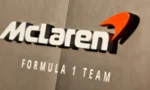 McLaren Formula 1 Team logo with orange swoosh on a wall.