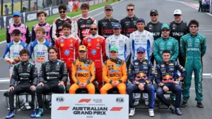 Group photo of Formula 1 drivers in racing suits posing on a track behind a banner reading Australian Grand Prix, with two rows of teams.