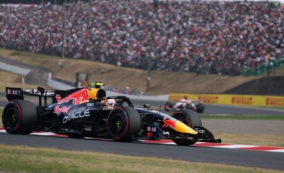 Red Bull Formula 1 car speeding on a race track with a crowded grandstand in the background.