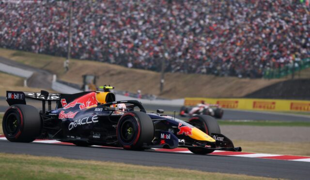Red Bull Formula 1 car speeding on a race track with a crowded grandstand in the background.