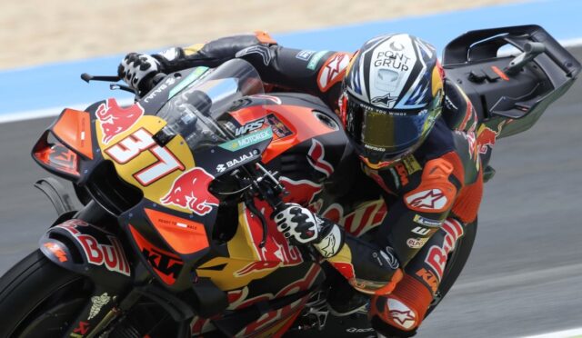 Motorcycle racer leaning into a turn on a red and yellow Red Bull KTM bike, number 37, helmet in racing colors.