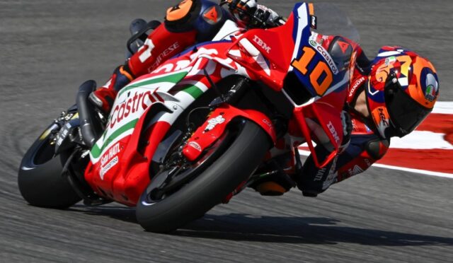 Motorcycle racer in red Castrol livery leaning into a turn, number 10, on a race track.