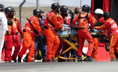 Team of emergency responders in orange suits loading a patient on a stretcher into a service vehicle.