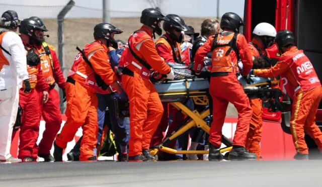 Team of emergency responders in orange suits loading a patient on a stretcher into a service vehicle.