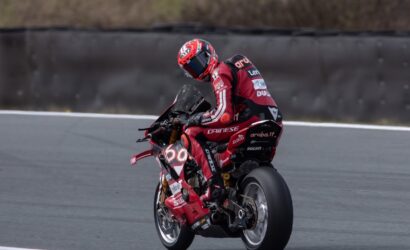 MotoGP rider in red Ducati livery leans into a turn on a racing track