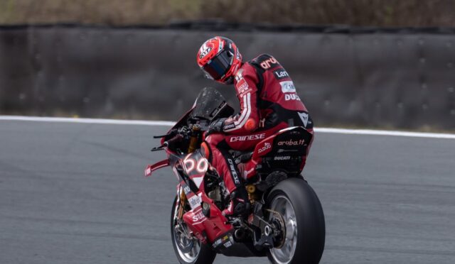 MotoGP rider in red Ducati livery leans into a turn on a racing track