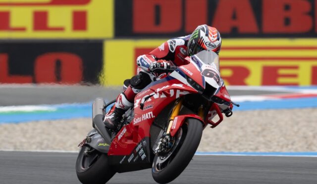 MotoGP rider in a red racing suit leaning into a corner on a red Honda motorcycle with number 93 shown on the front.
