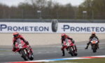 Three motorcycle racers lean into a curve on a track, with a Prometeon banner in the background.