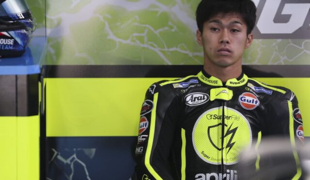 Motorcycle racer in neon-yellow and black racing suit stands against a lime backdrop with sponsor logos visible on the suit.