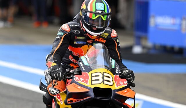 Professional motorcycle racer on an orange KTM bike with Red Bull branding, number 33, wearing a helmet and race suit on the track.