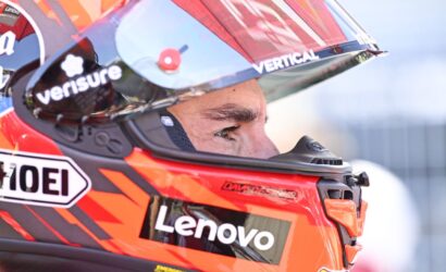 Close-up of a race car driver wearing a red helmet with Lenovo branding