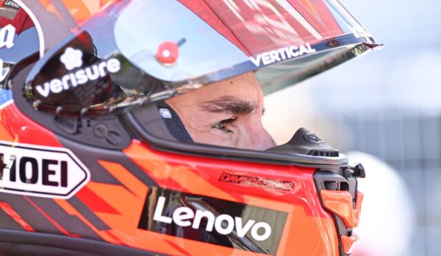 Close-up of a race car driver wearing a red helmet with Lenovo branding