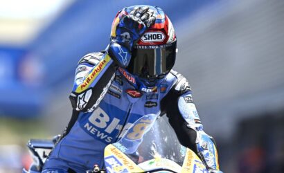 Moto motorcycle racer in blue race suit on a track, helmet branded SHOEI and Red Bull logos visible on bike and gear