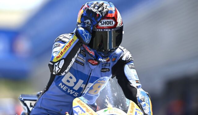 Moto motorcycle racer in blue race suit on a track, helmet branded SHOEI and Red Bull logos visible on bike and gear