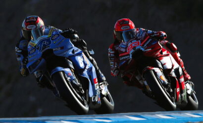 Two motorcycle racers in blue and red leathers leaning into a curve on a racetrack.