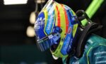 Colorful race helmet close-up with sponsor logos on a teal racing suit (side profile).