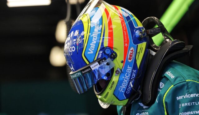 Colorful race helmet close-up with sponsor logos on a teal racing suit (side profile).