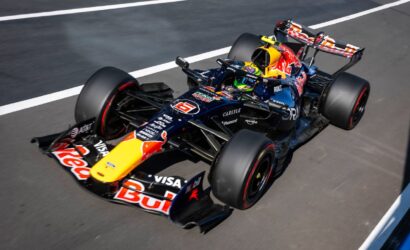 Red Bull Racing Formula 1 car on a race track with sponsor logos visible on the body and front wing, viewed from above.