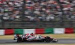 Formula 1 race car speeding on a track with a blurred grandstand and Italian flag-pattern barriers in the background.