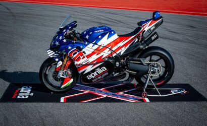 Aprilia racing motorcycle with star-spangled red, white, and blue livery on a track stand.