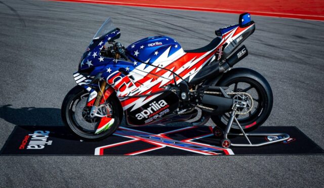 Aprilia racing motorcycle with star-spangled red, white, and blue livery on a track stand.