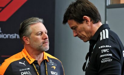 Two men in conversation, one in an orange Dell Technologies polo facing the other in a black polo with sponsor logos