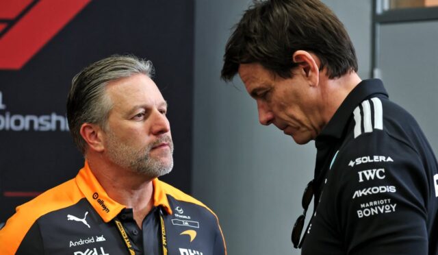 Two men in conversation, one in an orange Dell Technologies polo facing the other in a black polo with sponsor logos