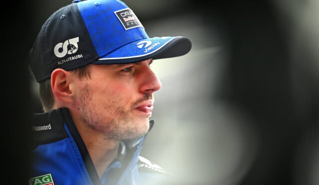Close-up of a man in a blue racing cap and jacket, gazing to the right.