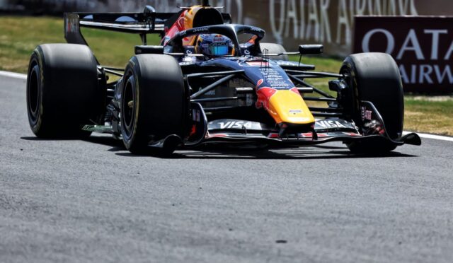 Red Bull Racing Formula 1 car speeding on a race track with large slick tires and a bright yellow nose cone, sponsor logos visible on the body.