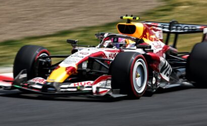 Red Bull Racing Formula 1 car speeding on a race track, showcasing red, white, and yellow livery and sponsor logos.