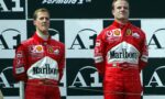Two Ferrari Formula 1 drivers in red Marlboro racing suits stand on a podium, facing forward against a black-and-white backdrop with sponsor logos.