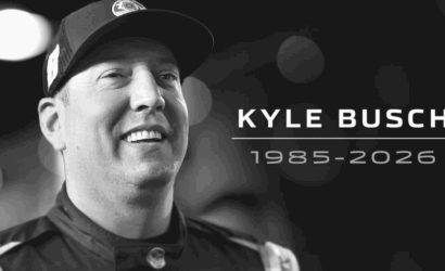 Tribute banner for NASCAR driver Kyle Busch, showing his name and the years 1985–2026 against a dark, bokeh background.