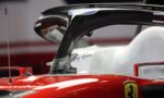 Close-up of a red Ferrari Formula 1 car cockpit with a carbon-fiber halo and Ferrari badge on the bodywork.