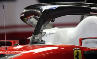 Close-up of a red Ferrari Formula 1 car cockpit with a carbon-fiber halo and Ferrari badge on the bodywork.