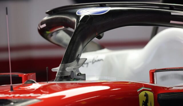 Close-up of a red Ferrari Formula 1 car cockpit with a carbon-fiber halo and Ferrari badge on the bodywork.