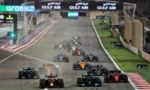 Nighttime Formula 1 race start with several cars lined up on the grid and the track lit up with sponsor banners along the pit straight.