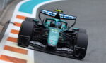 Formula 1 car in green livery rounds a corner on a racing track, sponsor logos visible on the nose and wings