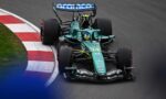 Green Formula 1 car seen from above turning into a curbed corner on a dark race track, sponsor logos visible on the nose and wings.