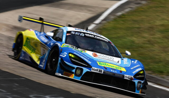 Blue and yellow race car taking a left-hand turn on a racetrack, sponsor decals visible on the bodywork and rear wing.