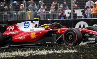 Red Formula 1 car with number 44 and prominent HP and Shell sponsor logos on a race track, spectators behind a chain-link fence watching.