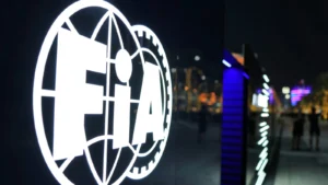 Illuminated FIFA logo with a globe and gear motif at night on an outdoor sign.