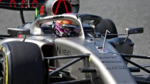 Close-up of a Formula 1 car cockpit with a driver wearing a purple helmet on the track
