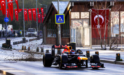Red Bull Formula 1 car racing down a city street lined with Turkish flags.
