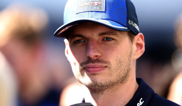 Close-up of a man in a blue cap with Oracle Red Bull Racing patch, speaking into a microphone during an interview.